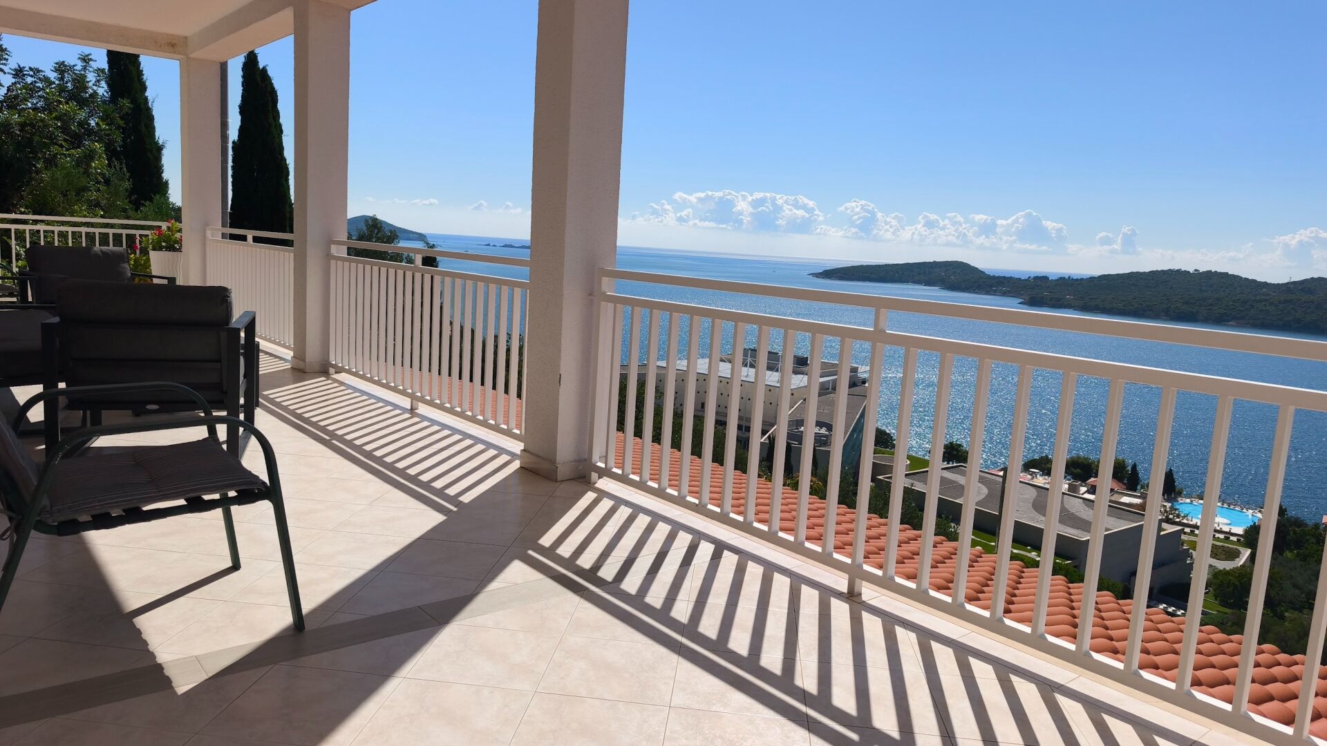 Un balcone con vista su un lago e montagne. Sono presenti due sedie e un tavolo.