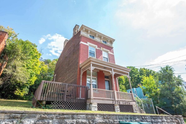 A two-story brick building with a porch and a stone wall in front.