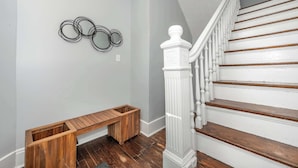A staircase with white balusters and wooden steps, a wooden bench, and a wall with three circular metal decorations.