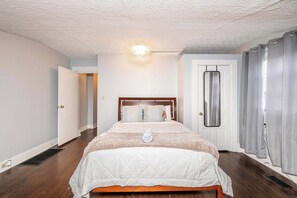 Ein Schlafzimmer mit einem hölzernen Bett, einer weißen Decke und einer Tür mit einem Metallgriff.