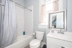 Ein Badezimmer mit einer weißen Badewanne, einer Toilette, einem Waschbecken mit Spiegel und einer Duschvorhang.