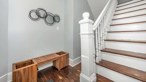 Un escalier avec des balustrades blanches et des marches en bois, un banc en bois et un mur orné de trois motifs métalliques circulaires.