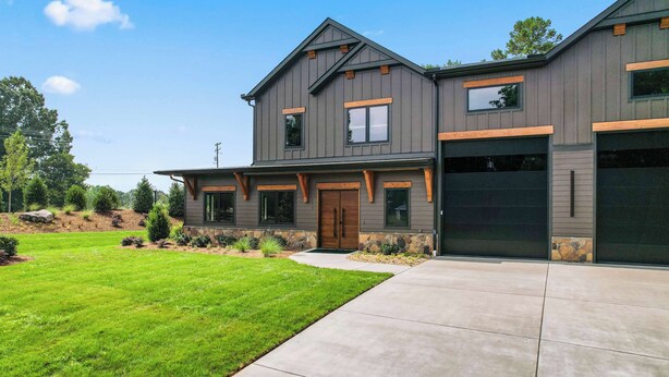 Une maison moderne à deux étages, dotée d’un grand garage, d’une pelouse bien entretenue et de fondations en pierre.