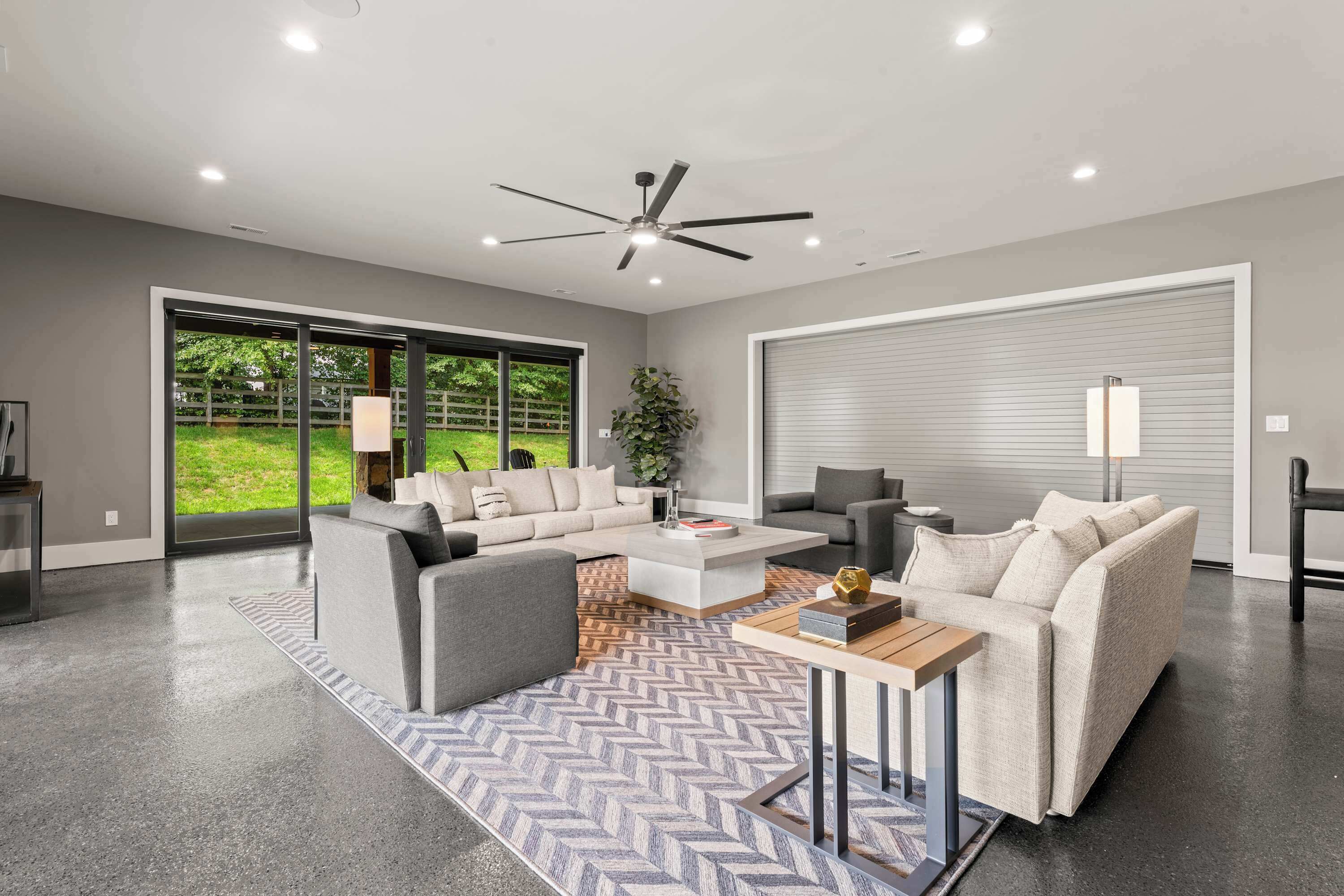 Ein geräumiges Wohnzimmer mit grauem Sofa, einem Couchtisch und einem Deckenventilator.