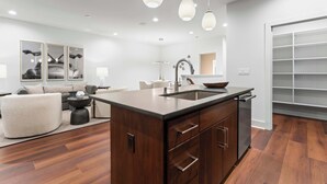 Une cuisine moderne dotée d’un îlot central, de meubles en bois et de luminaires suspendus.