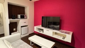 Una camera moderna con TV a schermo piatto, arredi bianchi e una parete decorata di rosso.