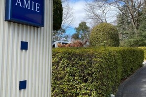 Un bâtiment sur lequel on peut lire l’inscription « AMIE », avec une haie au premier plan.