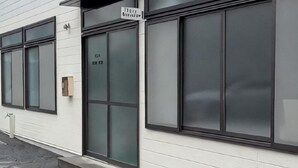 Un edificio con ampie vetrate, un ingresso con la scritta 'Hotel Reception' e un piccolo spazio esterno con posti a sedere.