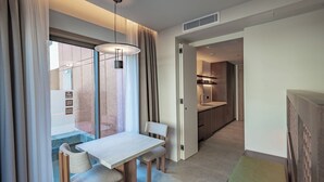 Een moderne hotelkamer met een eettafel, stoelen, uitzicht en een kitchenette.
