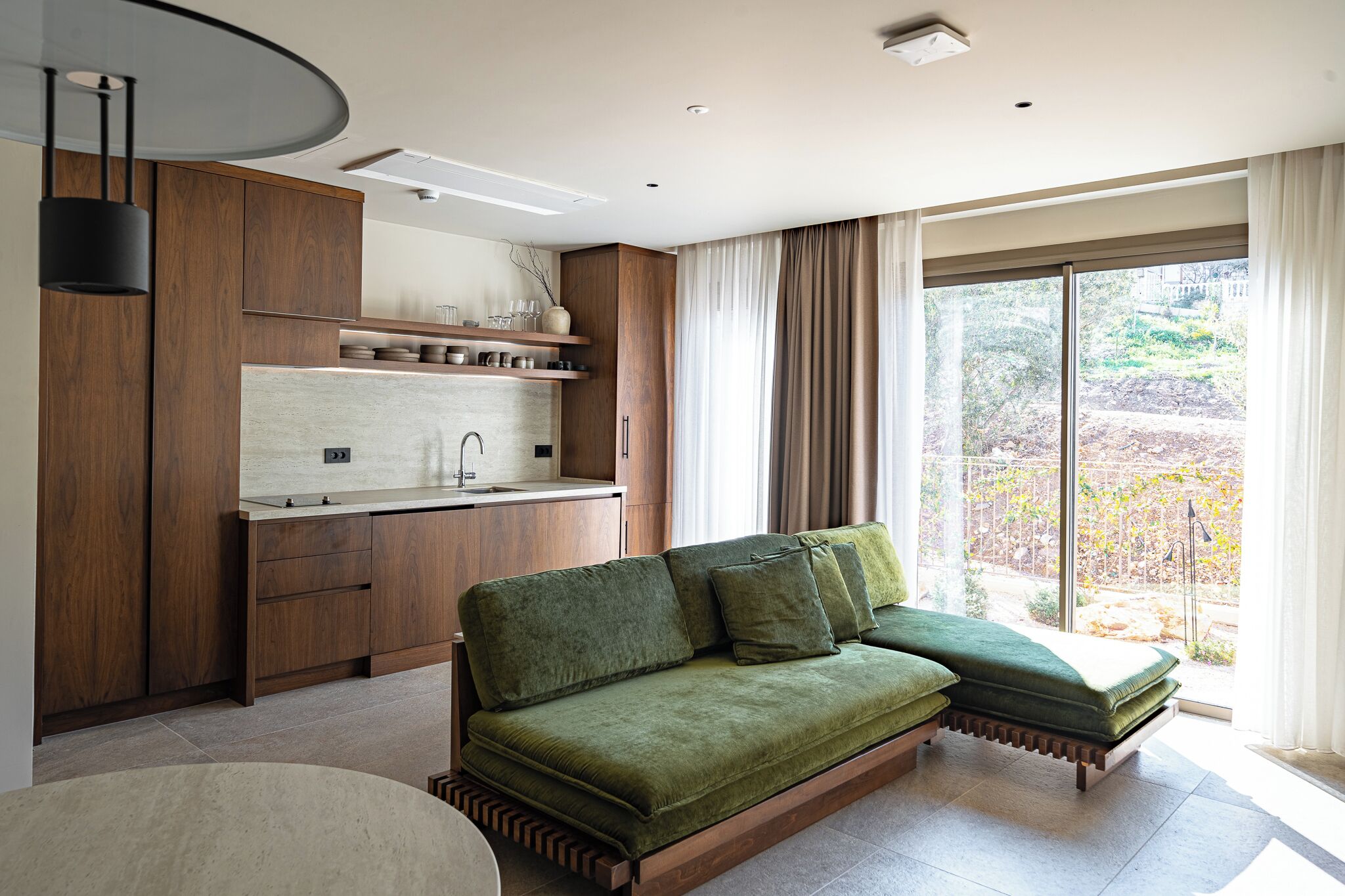 A modern kitchen with wooden cabinets, a built-in island, and a large window with curtains.