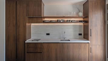A modern kitchen with wooden cabinets, a countertop, a sink, and a built-in shelf with glassware.