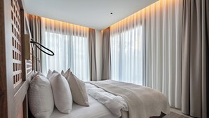 Een slaapkamer met een bed, gordijnen en een houten hoofdeinde.