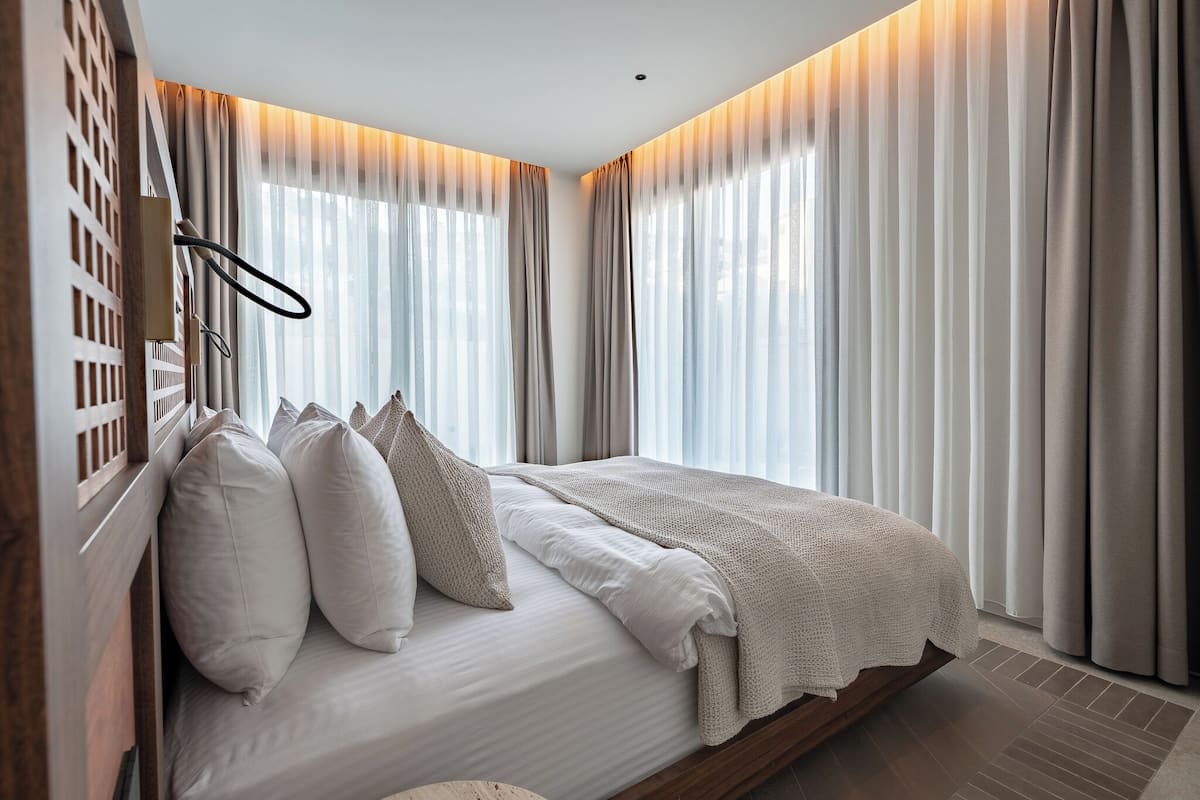 Une chambre à coucher avec un lit, des rideaux et une tête de lit en bois.