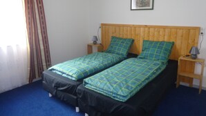 A double bed with a wooden headboard, two bedside tables with lamps, and a single wall-mounted picture. - Vacation cottage Van Wijk (Alheim)