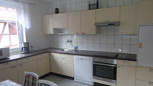 A kitchen with white cabinets, a dishwasher, an oven, and a coffee maker. - Vacation cottage Van Wijk (Alheim)