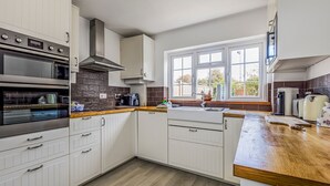 Una cucina moderna con mobili bianchi, un piano di lavoro in legno e un'ampia finestra che lascia entrare molta luce naturale.