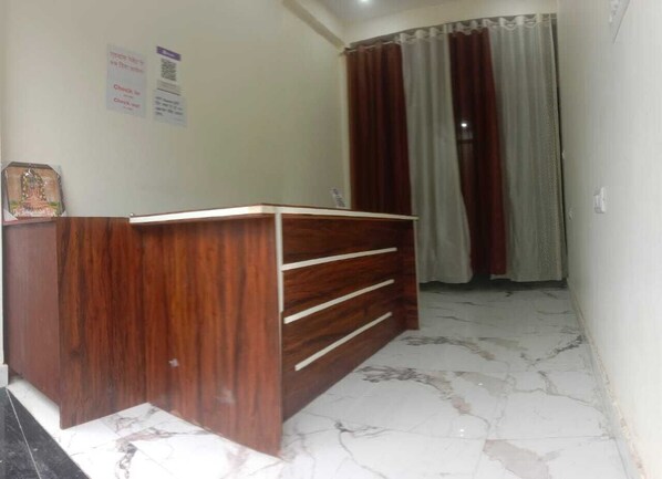A room with a wooden desk, a tiled floor, and a curtain. - Hotel Seva & Restaurant (Agra)