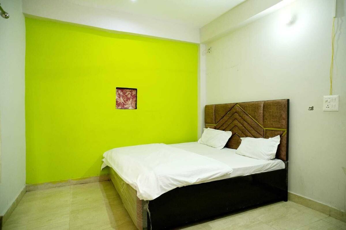 A room with a bed, a green wall, and a small decorative item.