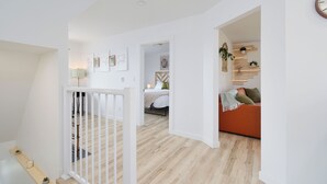 Un intérieur moderne comprenant un escalier, un lit et un coin salon avec des coussins.