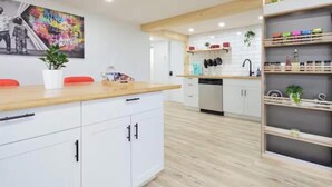 Eine moderne Küche mit weißen Schränken, Holz Arbeitsplatten und einem farbenfrohen abstrakten Gemälde an der Wand.