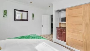 A bedroom with a bed, a wardrobe, a mirror, and a ceiling light fixture. - Victorian house (Sydney)