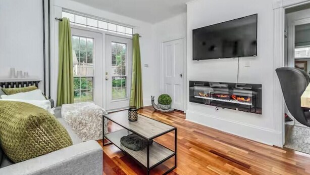 A modern living room with a fireplace, a flat-screen TV, and a large window with curtains. - Victorian house (Sydney)