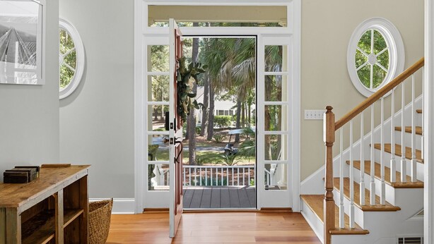 Una escalera de madera que conduce a un balcón con vista a una palmera y un puente.