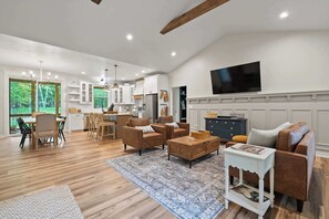 A spacious living room with a wooden floor, a large TV mounted on the wall, and a cozy seating area with leather sofas and a coffee table. - Dog-Friendly- EggHarbor w/ outdoor bar and grill (Egg Harbor)