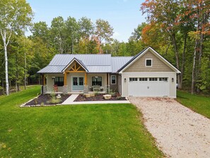 Ein zweistöckiges Haus mit Garage, Veranda und angelegtem Garten.