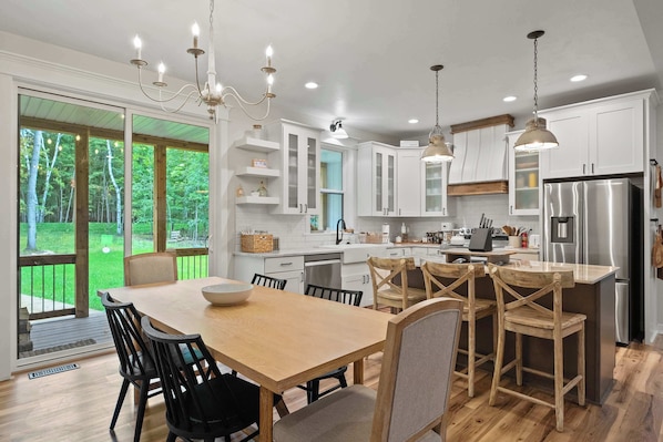 A modern kitchen with white cabinets, stainless steel appliances, and a wooden dining table with chairs.