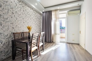 A dining area with a wooden table and chairs, a patterned wallpaper, and a view of the outdoors through a door. - Apartment by Luxe Group HH331 (Yerevan)
