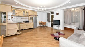 Un appartement moderne comprenant une cuisine, un coin repas et un salon. Il est équipé d’une table à manger avec des chaises, d’un canapé, d’une télévision et d’un petit balcon.