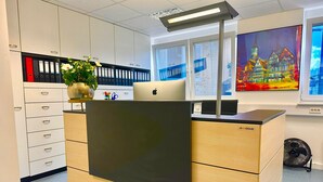 A reception desk with a laptop, a plant, and a framed picture on the wall. - Donau-Iller Vermietung 24  (Neu-Ulm)