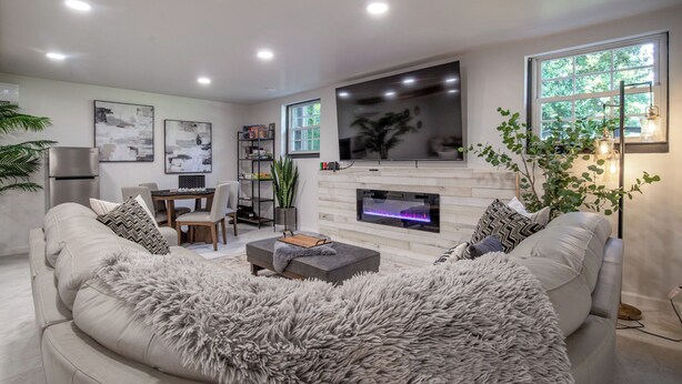 A modern living room with a fireplace, a sofa, and a dining area. - Pool, Pickleball, Poker, Ping-Pong! King beds! (Greer)