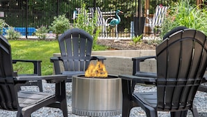 A patio area with three black chairs and a metal fire pit with flames. - Pool, Pickleball, Poker, Ping-Pong! King beds! (Greer)