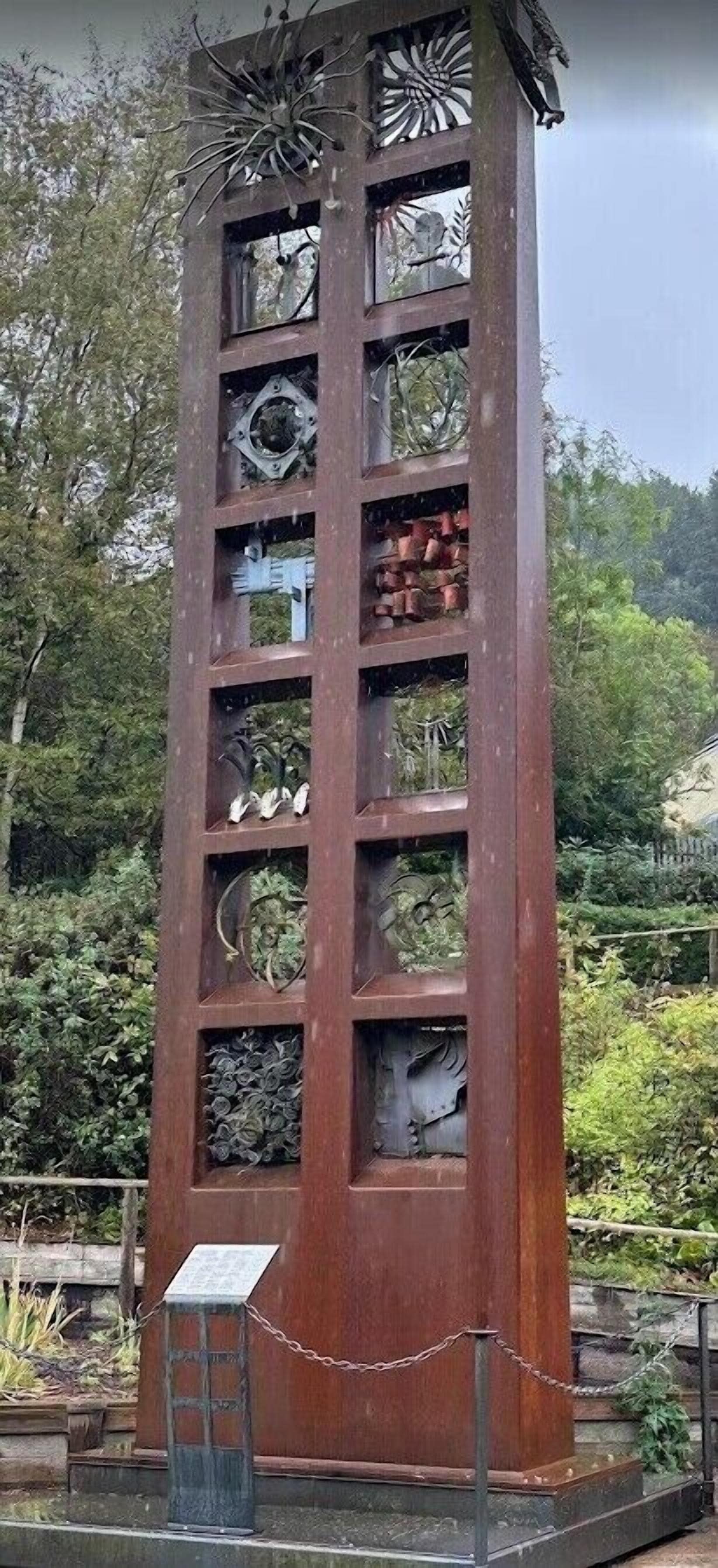 A tall, narrow metal structure with multiple panels, each containing different sculptures or artifacts.