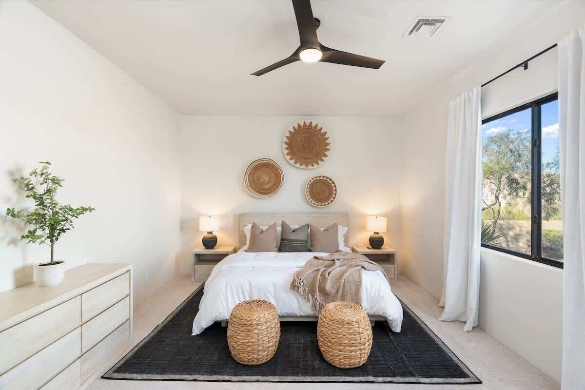 Ein Schlafzimmer mit Bett, Nachttischlampen, Deckenventilator und dekorativen Wandplatten.