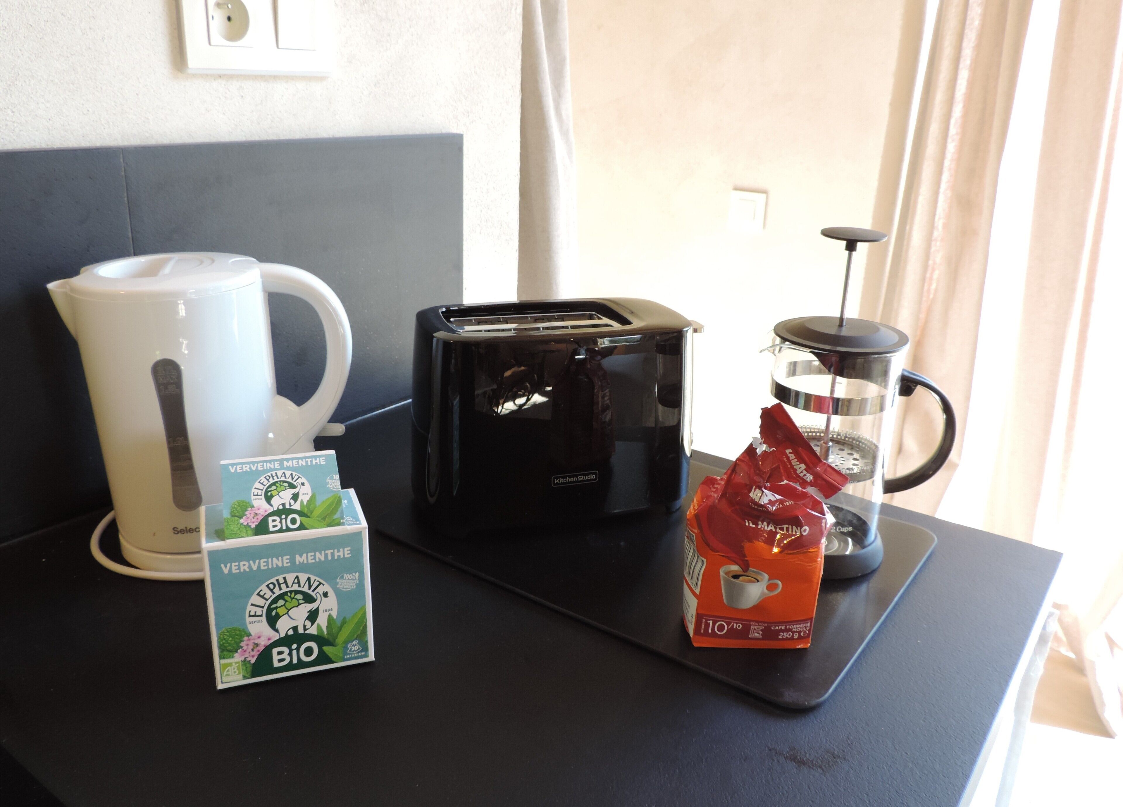 A kitchenette with a coffee maker, toaster, and a coffee pod box.