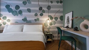 Un dormitorio con cama, mesita de noche y escritorio con silla.