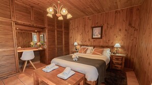 Een slaapkamer in houten stijl met een bed, nachtkastjes, een bureau en een stoel.
