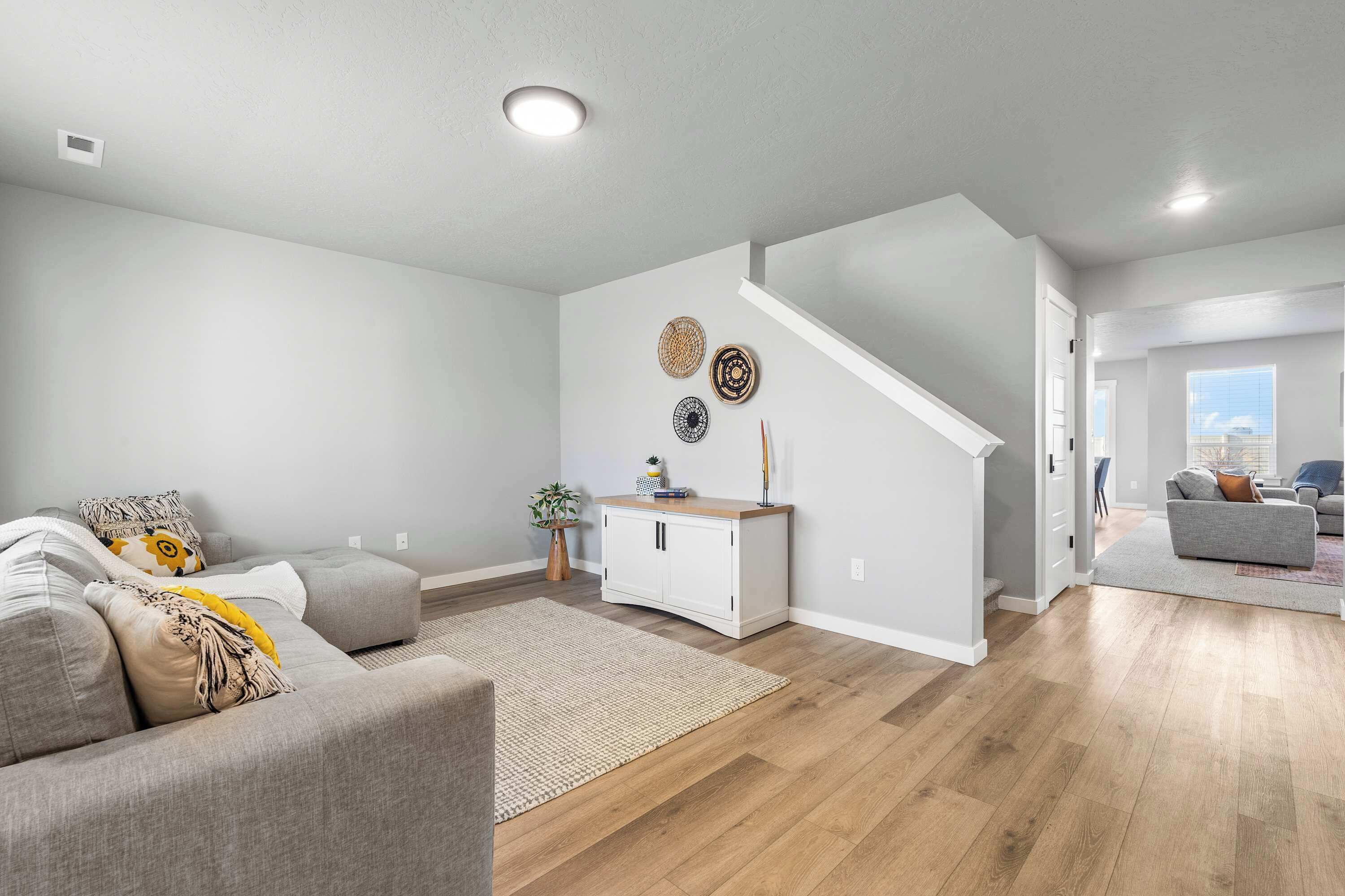 A modern living room with a sofa, a coffee table, a rug, a white cabinet, and a staircase.