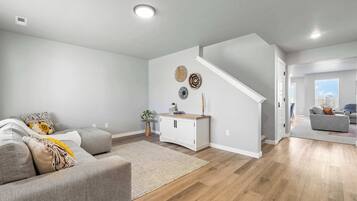 A modern living room with a sofa, a coffee table, a rug, a white cabinet, and a staircase.