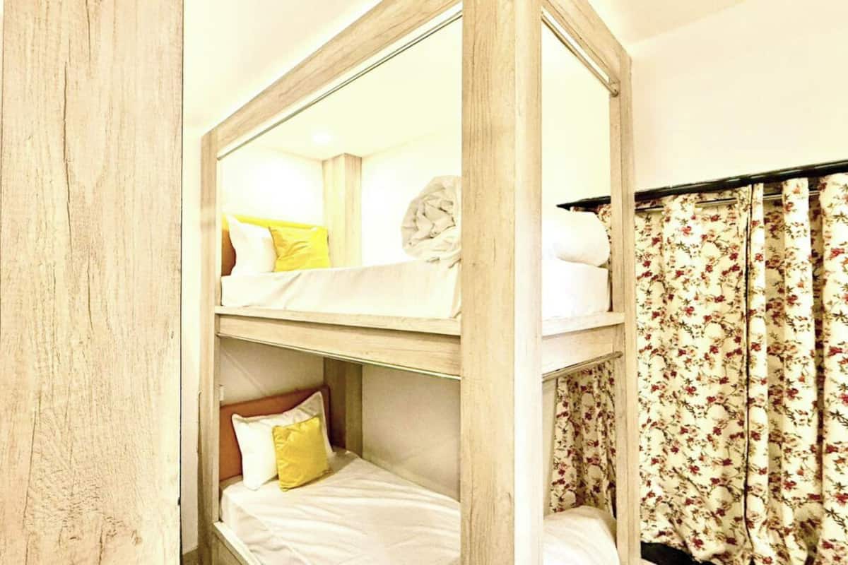 Una camera con letto a castello, struttura in legno, tende floreali e uno specchio che riflette l'ambiente.