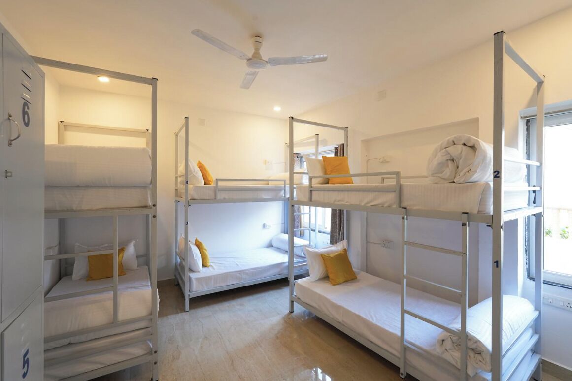 A dormitory room with bunk beds, a ceiling fan, and a window with a view.