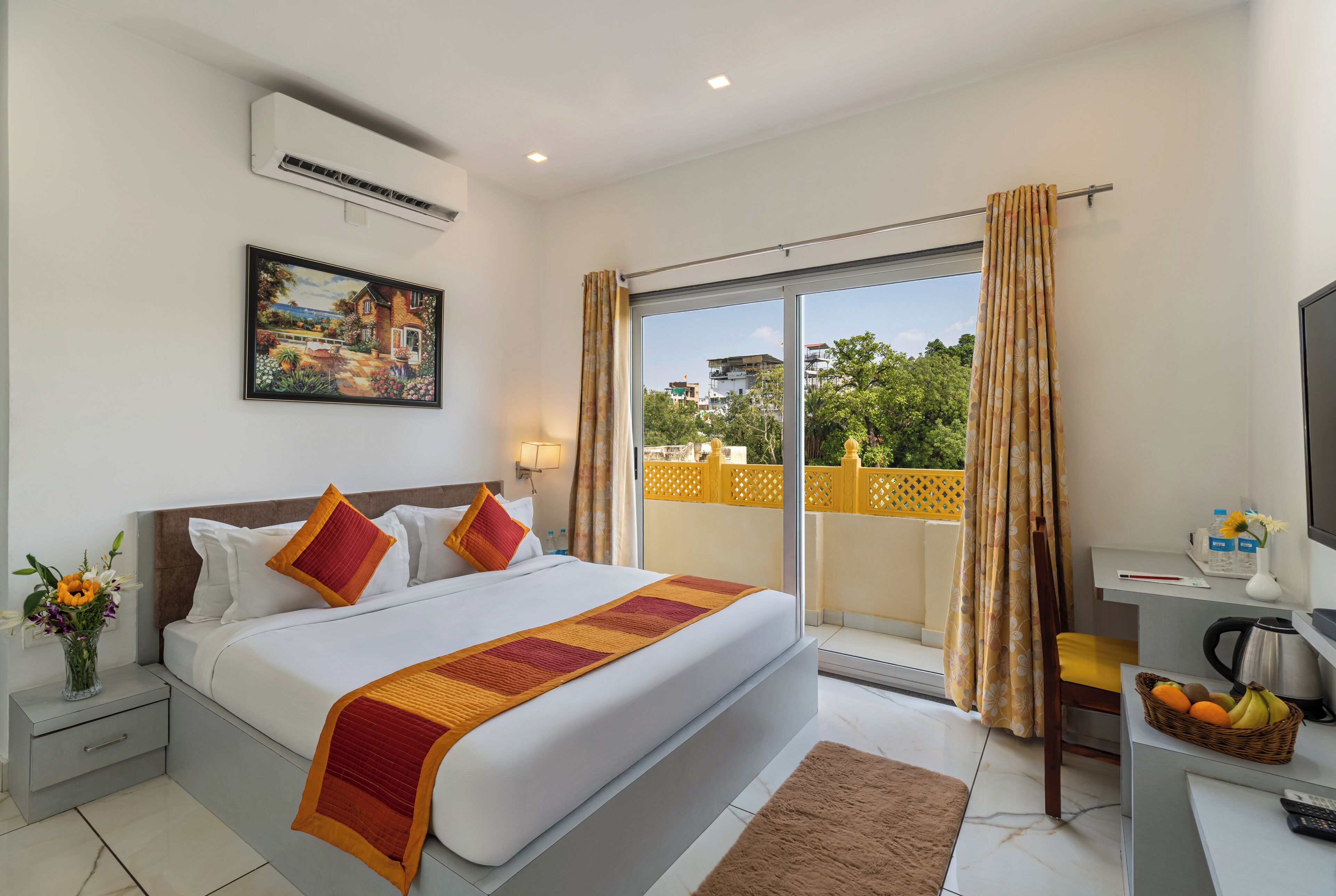 A hotel room with a large bed, a desk with a chair, a window with curtains, and a painting on the wall.