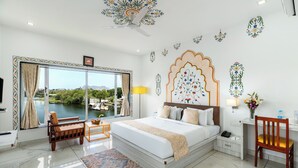 Une chambre d’hôtel avec une grande fenêtre, un lit, un bureau et une chaise.