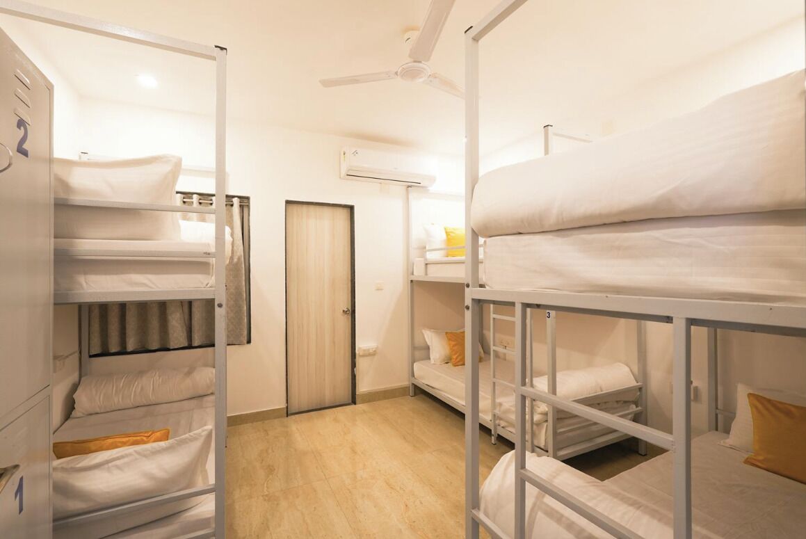 A dormitory room with bunk beds, a ceiling fan, and an air conditioning unit.