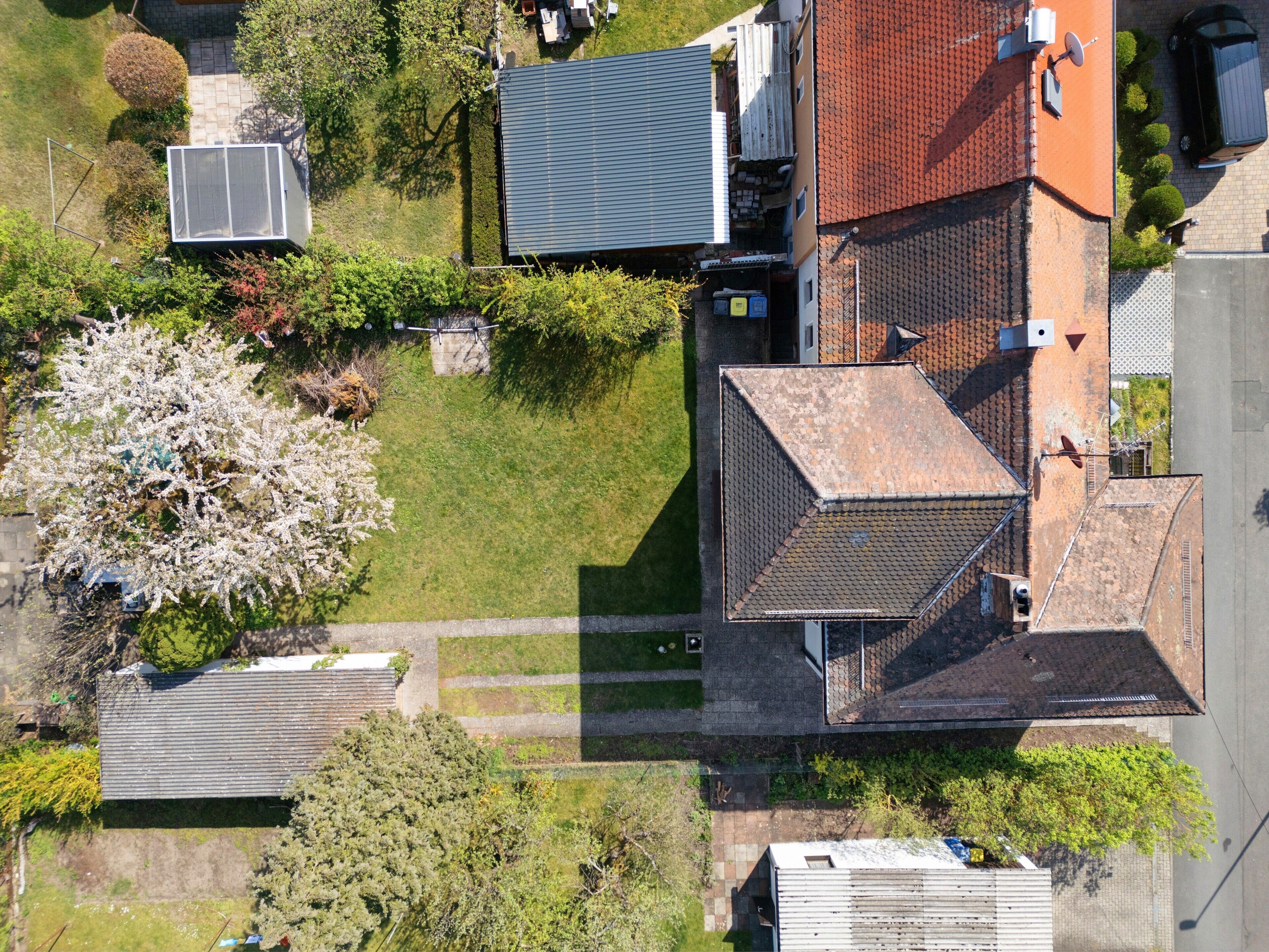 Luftaufnahme eines Wohngebiets mit Häusern, einer Solaranlage und einem Baum.