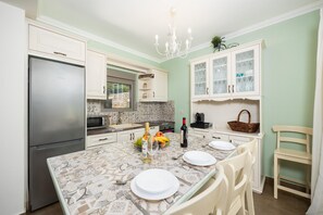 A kitchen with a central island, white cabinetry, a stainless steel refrigerator, and a chandelier.