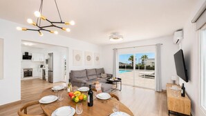 Ein modernes Wohnzimmer mit Essbereich, Küche und Blick auf einen Pool.